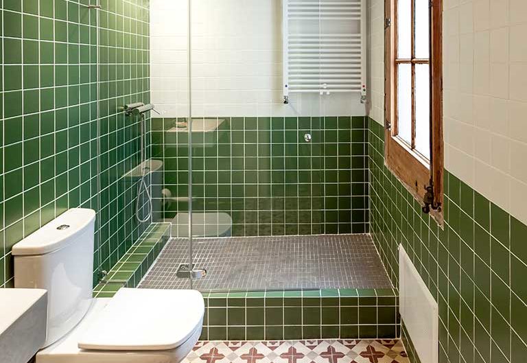 Baño reformado en Barcelona con ducha, revestimiento continuo y mobiliario a medida